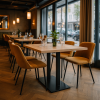Super-Seat | Houten tafels en zwart metalen onderstellen, mosterdgele stoelen, glas en planten in modern restaurant. | Horecameubilair