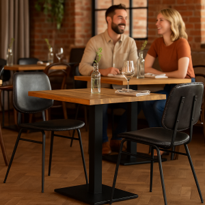 Super-Seat | Zwarte vintage stoelen van metaal en hout, glazen vaasje op houten tafel voor bakstenen muur. | Horecameubilair
