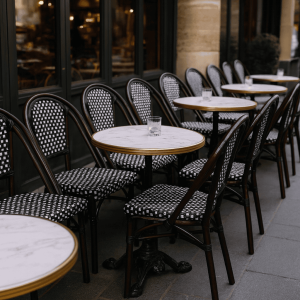 Super-Seat | Buiten een rij ronde marmeren tafels met zwarte rieten stoelen; op elke tafel een helder glas. | Horecameubilair