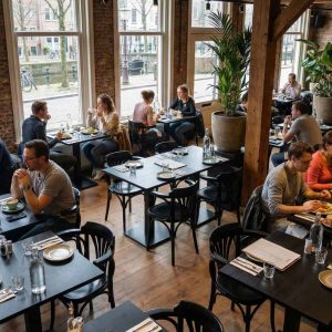 Super-Seat | Thon gebogen houten café armstoelen waaier zwart | Zwarte houten stoelen en tafels, groene planten, houten vloer en bakstenen muren. | Horecameubilair