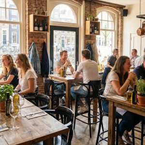 Super-Seat |Mensen dineren en kletsen in een gezellig restaurant met zwarte Thon barkrukken, houten tafels en planten op tafel. | Horecameubilair