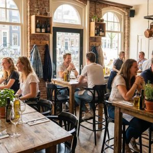 Super-Seat |Mensen dineren en kletsen in een gezellig restaurant met zwarte Thon barkrukken, houten tafels en planten op tafel. | Horecameubilair
