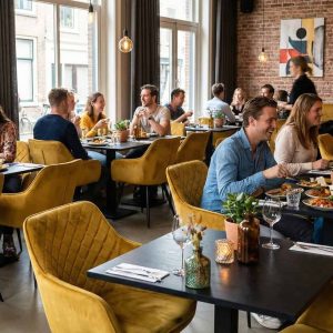Super-Seat | Diamond fluwelen horeca stoelen oker | Fluwelen okergele stoelen en houten tafels sieren het moderne restaurant met planten en grote ramen. | Horecameubilair