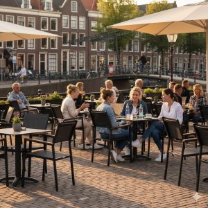 Super-Seat | Zwarte textilene stapelstoelen met arm, metalen tafels bij kanaal onder parasols. | Horecameubilair