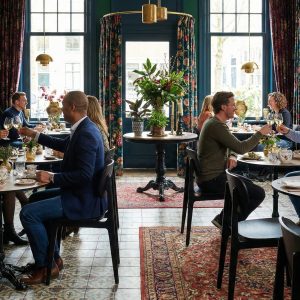 Super-Seat | Scandinavische design stoelen Bonn zwart Zwarte design stoelen en houten tafels in een licht restaurant met bloemen en grote ramen. | Horecameubilair