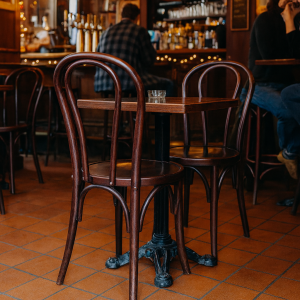 Super-Seat | Vienna Thon Stapelstoelen Donkerbruin | Donkerbruine houten stapelstoelen en tafel, glas water erop, op tegelvloer in café. | Horecameubilair