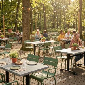 Super-Seat |Horeca terras Luxemburg|Groene armstoelen en houten tafels met planten, omgeven door bomen en sfeerverlichting. | Horecameubilair