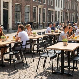 Super-Seat |Houten stoelen, koperkleurige tafels 70x70cm, roest look, mensen eten buiten op klinkerstraat. | Horecameubilair