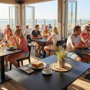 Super-Seat | Zwarte melamine tafels 120x67cm met metalen onderstel, uitzicht op zee, lichte strandstoelen. | Horecameubilair