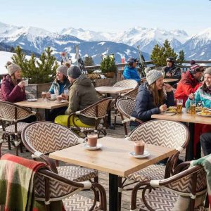 Super-Seat | Boho beige stoelen met armdekens, houten tafels en krukken op besneeuwd terras, mensen in winterkleding. | Horecameubilair