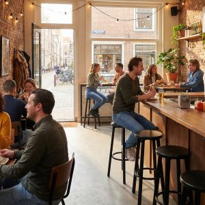 Super-Seat | Zwarte metalen barkrukken aan houten tafels in knus restaurant met bakstenen muren en grote ramen. | Horecameubilair