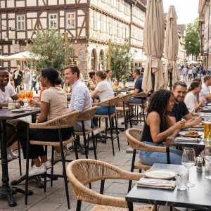 Super-Seat | Terras Barkrukken Zwarte Praag barkrukken van vlechtwerk met armleuning, houten tafels en terracotta potten op kinderkopjes. | Horecameubilair