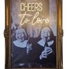 Super-Seat | Ingelijste zwart-wit foto van twee lachende nonnen die flessen vasthouden, met neon kunst 'CHEERS' in antieke houten gouden lijst Gouden antieke houten lijst, zwart-wit foto, neon CHEERS-tekst, vintage uitstraling. | Horecameubilair