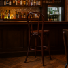 Super-Seat | A Vienna Thon no 18 houten barkrukken bruin | Bruine houten barkrukken bij donkerhouten bar, glazen en flessen op planken, warme verlichting. | Horecameubilair