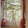 Super-Seat | Twee witte metalen stoelen op balkon, kijkend op groene bomen, rood gordijn. | Horecameubilair