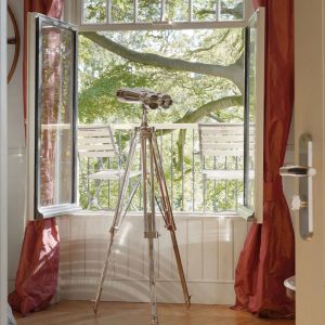 Super-Seat | Twee witte metalen stoelen op balkon, kijkend op groene bomen, rood gordijn. | Horecameubilair