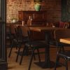 Super-Seat | Jody horeca design stoelen zwart/bruin | Zwarte en bruine stapelbare stoelen van hout/leer, houten tafels, leren bank, bakstenen muur. | Horecameubilair
