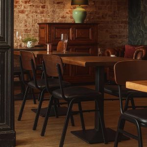 Super-Seat | Jody horeca design stoelen zwart/bruin | Zwarte en bruine stapelbare stoelen van hout/leer, houten tafels, leren bank, bakstenen muur. | Horecameubilair