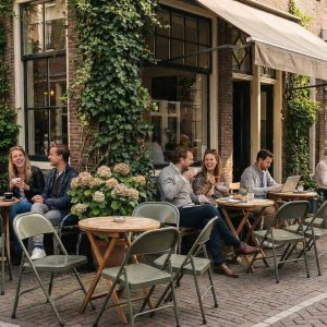 Super-Seat | Metalen legergroene klapstoelen en tafels op kinderkopjes, mensen genieten buiten. | Horecameubilair