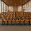Super-Seat | Bruine houten stoelen met zwart frame in lichte zaal met tapis, houten plafond en hoge ramen. | Horecameubilair