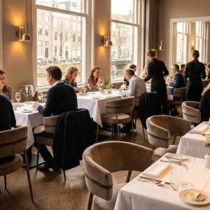 Super-Seat | Mounira Design Fluwelen mokka armstoelen met gouden details, witte tafels en bloemstukken in licht restaurant aan het water. | Horecameubilair