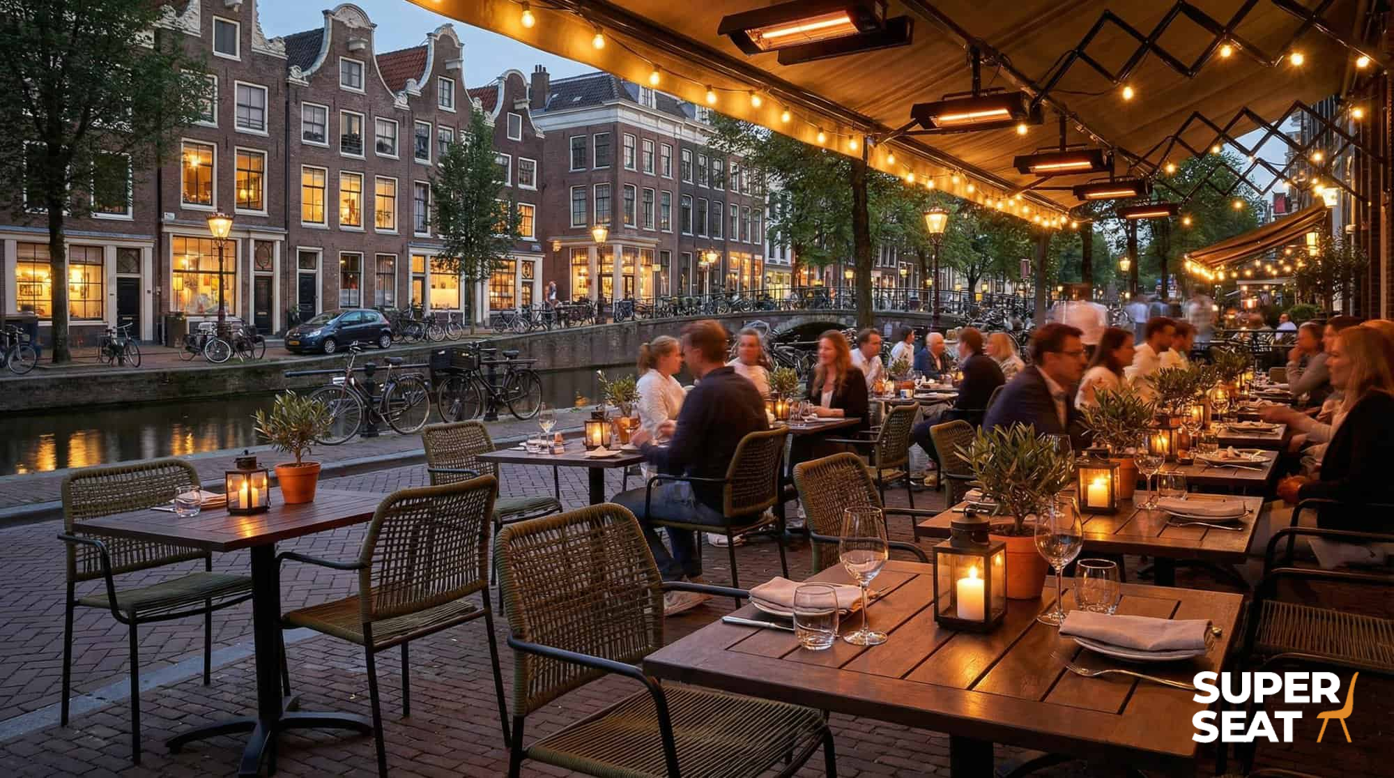 Super-Seat | Outdoor terrasstoelen Harper groen kunststof met arm, metalen tafels, stringlights; oude panden langs de gracht. | Horecameubilair