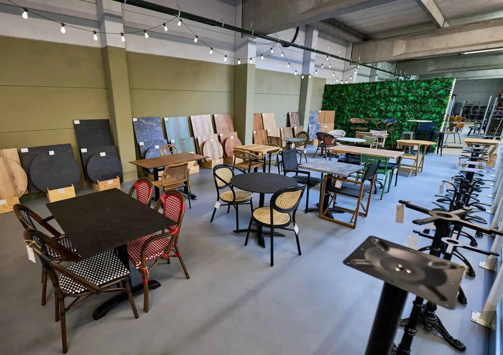 Super-Seat | Meubelbezoek showroom | Diverse houten tafels en stoelen, barkrukken, materiaalstalen en groene plantenwand met sfeerverlichting. | Horecameubilair