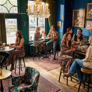 Super-Seat | Zwarte en okergele velours barkrukken, houten tafels, metalen stoelen in kleurrijk café. | Horecameubilair